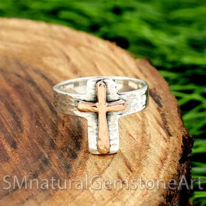 Puede incluir: Un anillo de plata con textura martillada y un diseño de cruz de oro rosa.