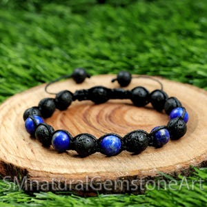 May include: A black lava rock and blue lapis lazuli beaded bracelet with a knotted cord closure.