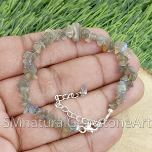 May include: A silver chain bracelet with a clasp fastening. The bracelet is made with small, irregular pieces of labradorite gemstone in shades of grey and blue.