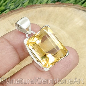 May include: A silver pendant featuring a large, faceted, yellow citrine gemstone in a square shape.
