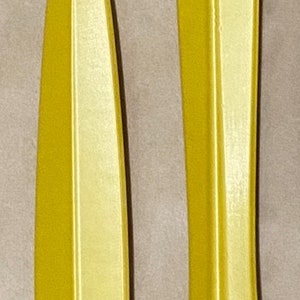 May include: Two yellow plastic knife handles, one with a blade and one without. The handle without a blade has two small holes at the top.