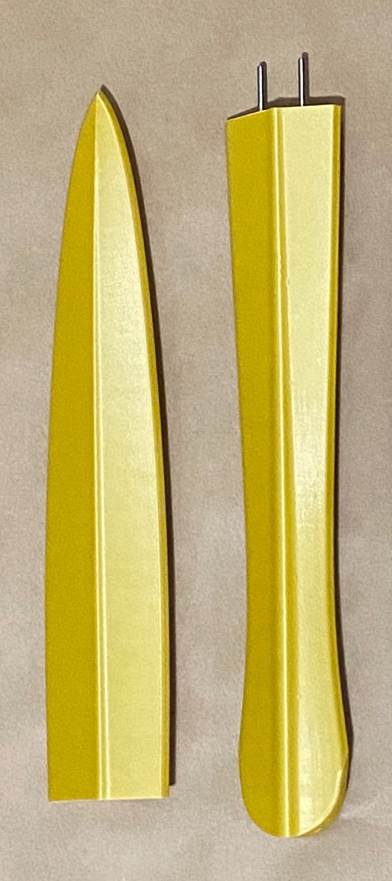 May include: Two yellow plastic knife handles, one with a blade and one without. The handle without a blade has two small holes at the top.