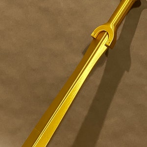 May include: A gold-colored sword with a decorative hilt and a straight blade.