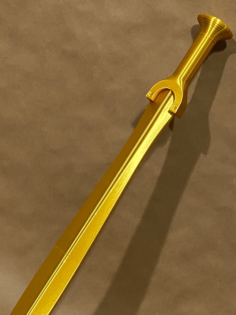 May include: A gold-colored sword with a decorative hilt and a straight blade.