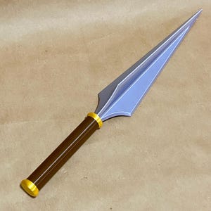 May include: A spear with a brown handle and a light blue blade. The handle has a gold-colored ring near the blade and at the base. The spearhead is a light blue color with a pointed tip. The spear is a decorative item.