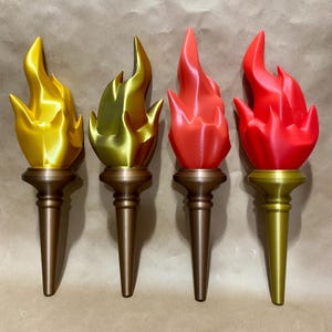 May include: Four decorative torch replicas in gold, bronze, and red. Each torch features a flame design atop a detailed stem. The torches are arranged in a row, showcasing their varying colors and finishes.