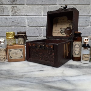 May include: A collection of miniature potion bottles, jars, and a wooden chest. The bottles have labels with various names, and the chest is dark brown with the letters "HP" on the side. The background is a light gray brick wall.