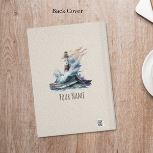 Puede incluir: Una ilustraci&oacute;n de acuarela de un faro en una costa rocosa con olas rompiendo. El texto "YOUR NAME" est&aacute; impreso debajo de la imagen.