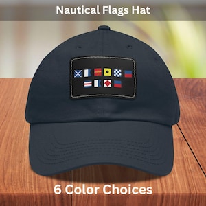 May include: A navy blue baseball cap with a patch of nautical signal flags. The patch features a variety of coloured flags with different symbols. The text "Nautical Flags Hat" is at the top of the image and "6 Colour Choices" is at the bottom.