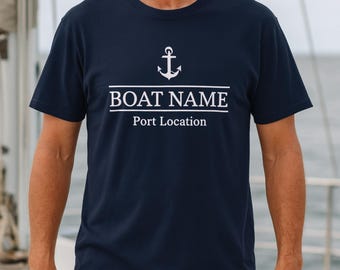 May include: Navy blue t-shirt with a white anchor graphic above the text "BOAT NAME" and "Port Location". The shirt is a crew neck style.
