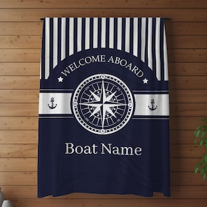 May include: A blue and white striped nautical themed throw blanket with a compass and anchor design. The text "Welcome Aboard" and "Boat Name" are printed on the blanket.
