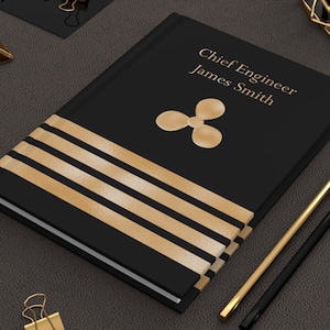 May include: Black leather journal with gold stripes and a gold propeller design. The text "Chief Engineer James Smith" is printed on the cover.