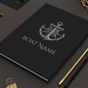 May include: Black notebook with a gold anchor and gear design. The text "BOAT NAME" is printed in gold on the cover.