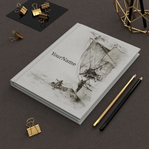 May include: A white journal with a black and white sketch of a sailboat on the cover. The text "YourName" is printed on the cover.