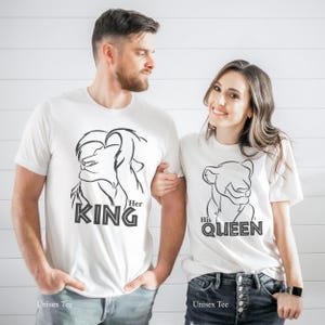 May include: White unisex t-shirts with black lion graphics. One shirt reads "Her KING" and the other reads "His QUEEN". The shirts are worn by a couple. The text "Unisex Tee" is printed at the bottom of each shirt.