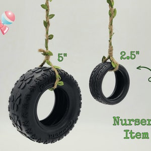 May include: Two black tire swings, one 5 inches in diameter and the other 2.5 inches in diameter, hanging from rope with green leaves.  Nursery Item.