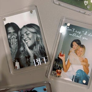 May include: Several clear acrylic photo frames with images of friends. One frame has the word "BFF" in white. Another frame has the text "Can't say 'I do' without you". The photos are in color and black and white.