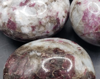May include: Four tumbled stones with a white, gray, and pink color pattern. The stones have a smooth, polished surface.