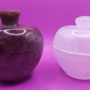 May include: Two decorative apple-shaped containers. One is made of brown and white marble and the other is made of white alabaster.