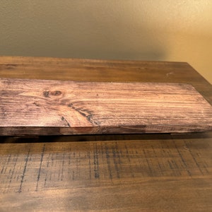May include: A dark brown wooden shelf with a natural wood grain pattern. The shelf is stained and has a smooth finish.