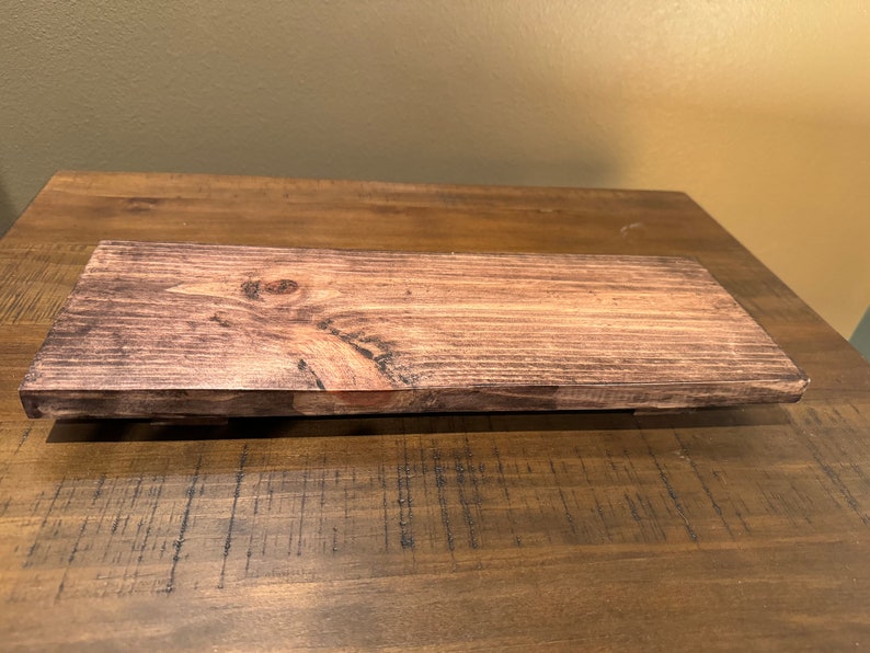 May include: A dark brown wooden shelf with a natural wood grain pattern. The shelf is stained and has a smooth finish.