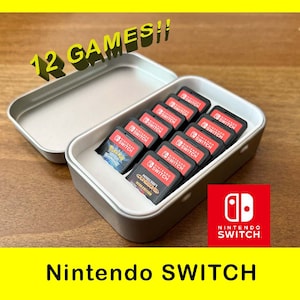 May include: A silver metal case filled with twelve Nintendo Switch game cartridges. The case is open and the cartridges are visible. The Nintendo Switch logo is visible in the lower right corner of the image.
