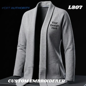 May include: A gray, open-front cardigan with long sleeves and two front pockets. The text "Your Design Here" is printed on the front. The words "PORT AUTHORITY", "L807", and "CUSTOM EMBROIDERED" are also visible.
