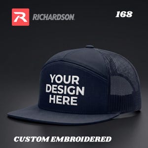 Może przedstawiać: Granatowa czapka typu trucker z płaskim daszkiem i siatkowym tyłem. Na przednim panelu widnieje biały napis "YOUR DESIGN HERE". Czapka ma również napis "CUSTOM EMBROIDERED" i numer "168". Widoczne jest logo Richardson.