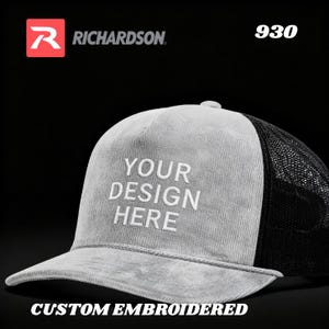 May include: A grey corduroy trucker hat with a black mesh back and white embroidered text on the front that reads YOUR DESIGN HERE. The hat features a Richardson logo and the number 930 in the upper corners, with the text CUSTOM EMBROIDERED below.