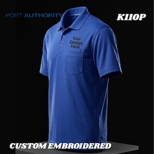 May include: A royal blue polo shirt with a pocket and the text "Your Design Here" embroidered on the pocket. The shirt has a classic collar and short sleeves. The text "PORT AUTHORITY" and "CUSTOM EMBROIDERED" are also visible.
