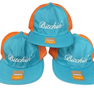 May include: Three turquoise baseball caps with orange mesh back panels. Each cap features the word Bitchin' embroidered in white script on the front crown and a rectangular Richardson brand sticker on the flat brim of each hat.