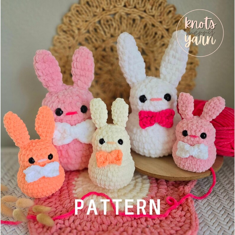 May include: A crochet pattern for making four bunny amigurumi toys. The bunnies are in pink, white, and cream colors with orange and pink bows. The pattern is called "PATTERN" and is from the shop "knots n' yarn".