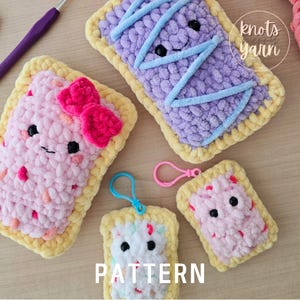 May include: Four crocheted stuffed toys shaped like Pop-Tarts with different colored fillings and faces. The toys are on a wooden surface with the text "knots yarn" and "PATTERN" on the surface.
