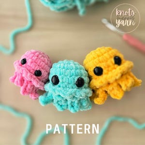 May include: Three small, plush, crocheted octopus toys in pink, turquoise, and yellow. Each octopus features large, round, black safety eyes and textured, soft yarn. The word PATTERN is printed in white at the bottom, with a logo in the corner.