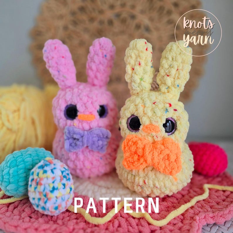May include: Two crocheted Easter bunny plushies, one pink with a purple bow and one yellow with an orange bow. The bunnies are sitting on a pink and yellow crocheted surface. The text "knots yarn" is visible in the upper right corner of the image. The text "PATTERN" is visible in the lower center of the image.