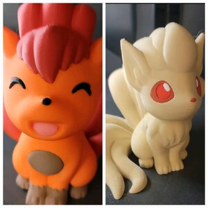 May include: Two 3D printed figurines of Pokemon characters. The first is a red and orange Vulpix with a brown spot on its belly. The second is a white and cream colored Ninetails with red eyes.
