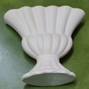 May include: White ceramic vase with a fluted design. The vase has a wide, flared opening and a round base.