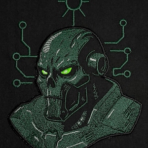 Könnte beinhalten: Ein gestickter Aufnäher auf schwarzem Stoffhintergrund, der einen dunkelgrünen Cyborg-Schädel mit leuchtend hellgrünen Augen zeigt. Das Design umfasst ein kreisförmiges Symbol mit strahlenden Linien über dem Kopf und Leiterplattenmuster an den Seiten.
