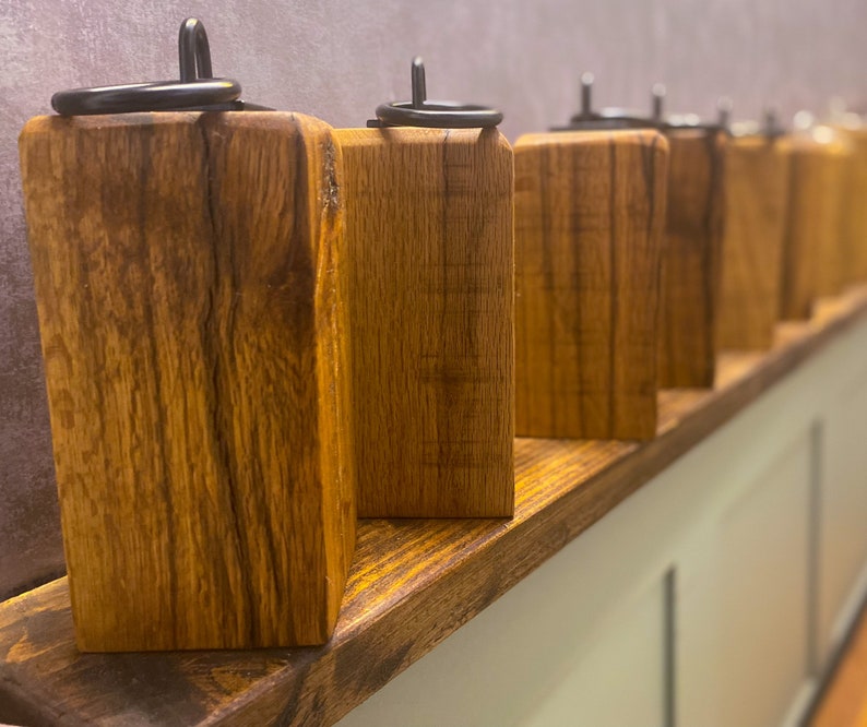 May include: A row of wooden candle holders with black metal rings on top. The holders are arranged on a wooden shelf.