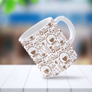 May include: White ceramic coffee mug with a brown and white pattern. The pattern features the text "The Coffee Shop" and coffee bean illustrations.