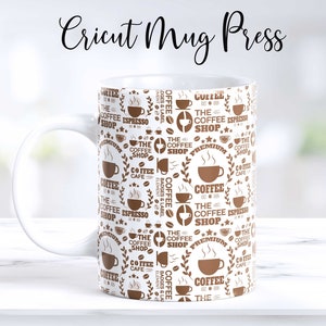 May include: White ceramic mug with a brown coffee shop design. The mug features a repeating pattern of coffee cups, coffee beans, and the text "The Coffee Shop".