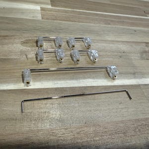 May include: A set of eight clear plastic curtain rod brackets with gold accents and two metal curtain rods. The rods are approximately 18 inches long.