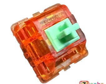 May include: Orange mechanical keyboard switch with a green stem and the word "EQUALZ" printed on the top.