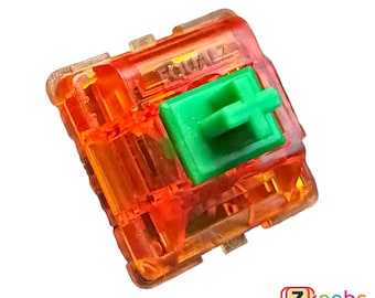 May include: A close-up of a transparent orange mechanical keyboard switch with a green stem. The switch has the text "EQUALZ" printed on the top.
