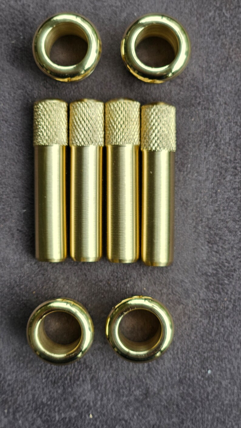 Puede incluir: Conjunto de seis ojales de metal dorado y cuatro varillas de metal dorado. Los ojales son redondos con un agujero en el centro. Las varillas son cil&iacute;ndricas con una superficie texturizada.