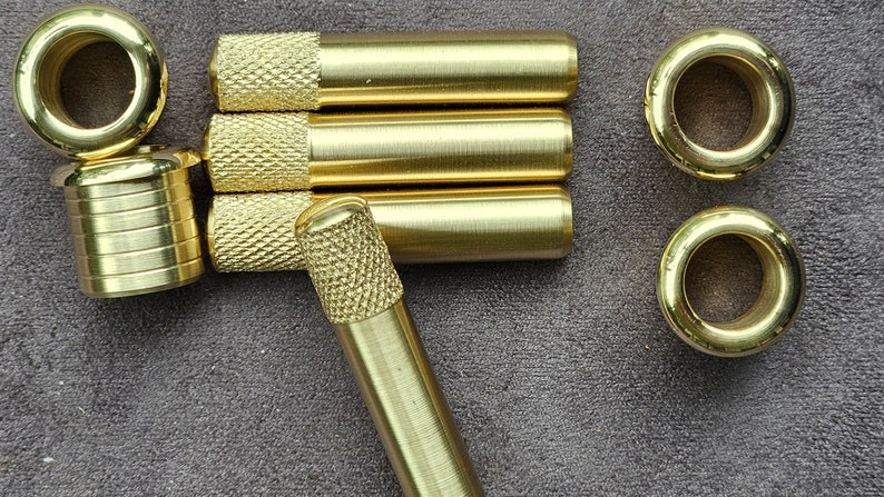 Puede incluir: Un conjunto de piezas de ferreter&iacute;a de lat&oacute;n que incluye tres varillas largas con extremos moleteados, una varilla corta con extremo moleteado, un anillo redondo con un agujero en el centro y un cilindro corto con una parte superior roscada.