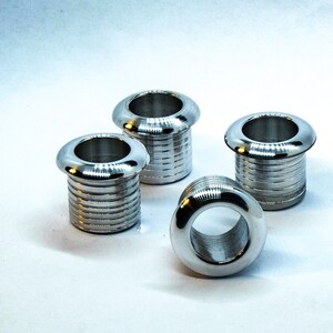 May include: Four silver metal grommets with a smooth, shiny finish. The grommets have a round, slightly raised lip around the opening.