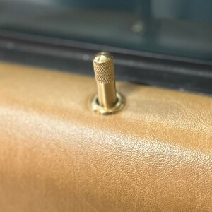 Puede incluir: Una manija de puerta dorada con un pomo moleteado.