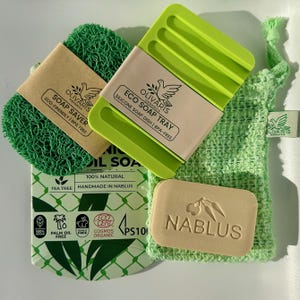 Puede incluir: Un juego de jabones ecológicos verdes que incluye un salvador de jabón, un jabonera de silicona, una pastilla de jabón y una bolsa de malla. La pastilla de jabón está estampada con "NABLUS". El juego incluye jabón de aceite de árbol de té y no contiene aceite de palma.