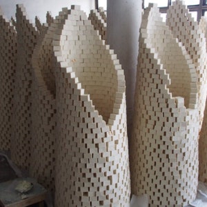 May include: A large group of white soap bars stacked in a curved, arch-like formation. The bars are arranged in a grid pattern, creating a unique and visually appealing display.